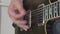 Person strikes the strings of electric guitar holding a pick in hand, close up. Musician is practicing or learning new