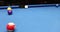 Person strikes white ball in American billiards