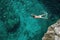A person in a swimsuit energetically swimming in the clear blue ocean water under a sunny sky, A swimmer diving into a crystal-