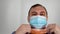 Person takes turns wearing medical masks of different colors. man in colored surgical masks.