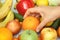 A person taking an orange out of a pile of fruit and vegetables