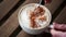 Person tasting cappucino with cinnamon