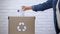 Person throwing plastic bottles into trash bin, sorting non-degradable waste