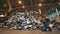 Person throws trash in a big pile at a recycling center.