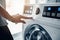 A person touching a button on a washing machine. AI generative image.