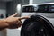 A person touching a button on a washing machine. AI generative image.