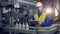 A person types on a tablet while checking work of factory conveyor.