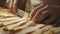 A person uses a knife to cut through a block of cheese on a wooden cutting board