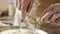 A person is using a knife to cut dough on a cutting board