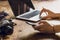 Person using laptop and smartphone at workspace with vintage camera