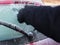 Person using a scrapper to scrape frost from the rear windscreen window of a red