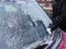 Person using a scrapper to scrape frost from the windscreen window of a red car