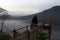 Person walking alone on natural wooden bridge in the mountain on misty morning at sunrise.