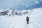 Person walking away down a snowy winter road through country fiel in a scenic landscape conceptual of the seasons