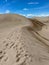 a person that is walking down a sand hill with footprints on it