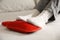 Person warming feet with hot water bottle on bed, closeup