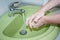 A person washes well-soaped hands under a tap with water