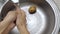 Person washing potatoes under water in sink