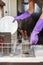 A person wearing purple kitchen gloves is placing a white porcelain plate into a compartment of under counter dish washer.