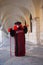 Person wearing a Venetian mask and a black and red costume under arches of Doges Palace at the Venice Carnival in Venice Italy