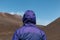 Person wearing a violet hooded outdoors sports jacket looking on the Etna volcano