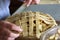 Person weaving dough strips on an apple pie