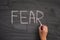 Person writing the word Fear on a blackboard