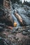 person in yellow jacket is sitting in front of a waterfall in austria