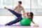 The personal coach helping woman in gym with stability ball