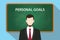 Personal goals white text illustration with a beard man wearing black suit standing in front of green chalk board