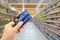 Personal hand holding credit card, with Abstract blurred supermarket view of empty supermarket aisle, defocused blurry background