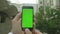 Personal perspective of a man using a Green-Screen smartphone outside the office