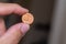 Persons hand holding out a fils coin, less than a dirham, the Currency of the United Arab Emirates -  on a brown background. Money