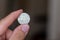 Persons hand holding out a five baht coin, the Currency of the Thailand -  on a brown background. Money exchange