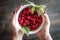 Persons hands hold white plate with red fresh raspberries