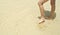 Persons legs standing in shallow water on white coral sand