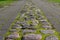 Perspective of country cobblestone road. Grass and moss sprout between the road stones