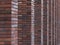 Perspective diagonal view on abstract brown red brick wall with columns with blured background. Architecture element brown brick w