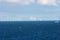 Perspective line of ocean wind mills with dark water and sky