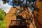 Perspective looking up at tall soutwestern stucco adobe building with balcony with corbels on a roof and trees framing the image u