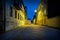 Perspective night view of a empty urban cobblestone street with moody lights.