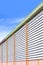Perspective side view of aluminum louver with gutter drainage system of warehouse building against blue sky