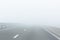 Perspective view of asphalt  empty road with guardrail and marking lines in a white fog