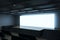 Perspective view on big blank white illuminated screen with place for your text or logo and blue backlit in empty huge hall with