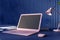 Perspective view on blank dark screen with space for your logo on modern pink laptop on dark table with notebooks and stylish lamp