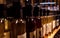 Perspective view of bokeh of liquor bottles in a shop over shelves. Translation of flowers in Spanish