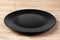 Perspective view. Empty dark matte dish for dinner on orange wooden background