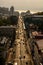 Perspective view of a long central city street with with silhouettes of cars and pedestrians people at sunset bright sun. Top view