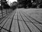 Perspective view of long iron fence casting a shadow on a asphalted footpath of a park..