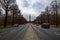 Perspective view from middle of wide road along Tiergarten park in Berlin Germany.  Cars are driving by road under dramatic sky.